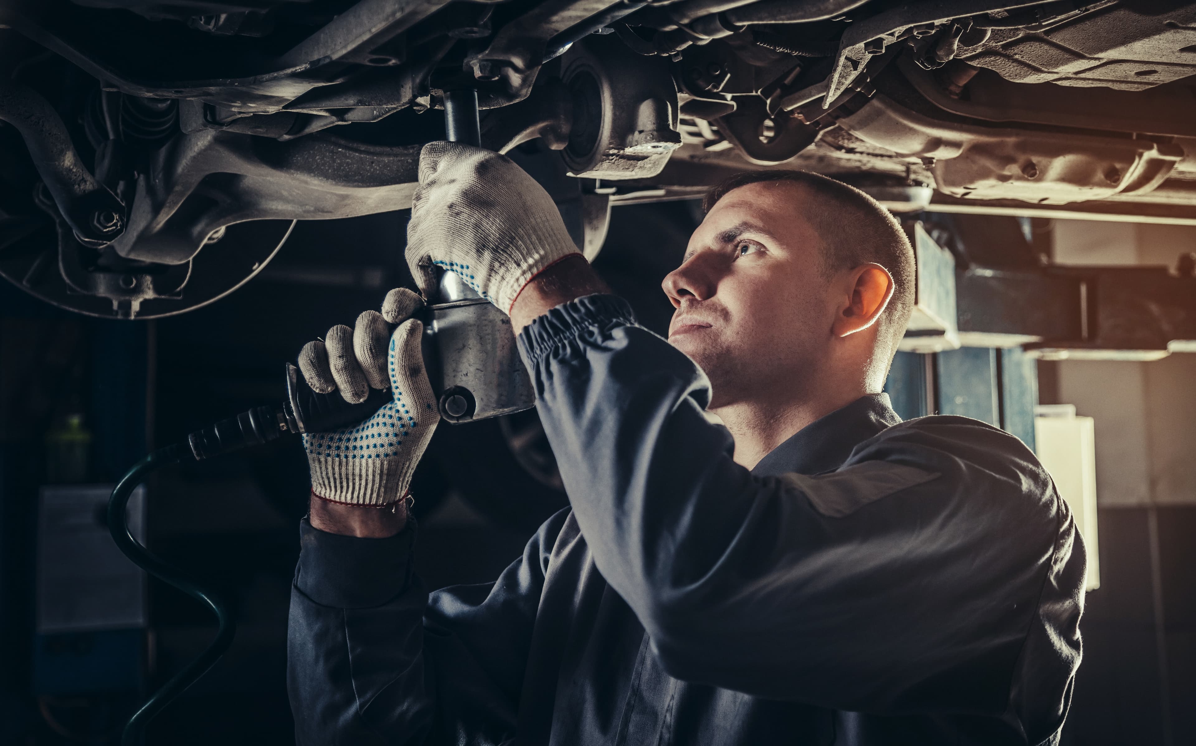 mechanic working on vehicle overhead