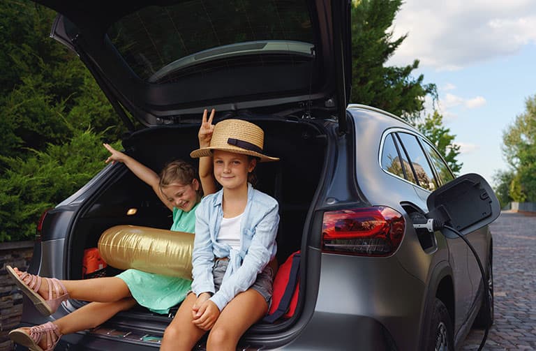 two happy kids sitting in the back of an electric vehicle